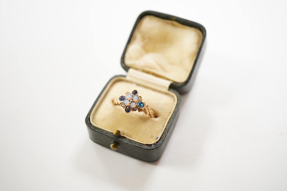 A late Victorian yellow metal, sapphire, opal and seed pearl cluster set dress ring, (one stone a paste replacement), size N, gross weight 2.2 grams.